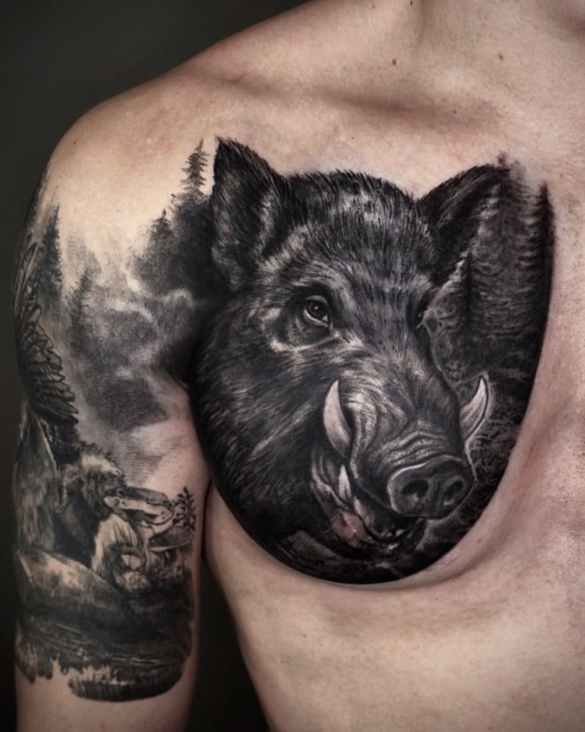 Tier Tattoo Deggendorf — fotorealistischer Black & Grey Wildschwein Brust Tattoo mit Wald und Wildschweinrudel, Tätowierer Deggendorf Luca Limito, Atelier Voltaire Tattoo Studio / Animal tattoo Deggendorf — photoreal black and grey wild boar chest tattoo with forest scene and boar family by Luca Limito at Atelier Voltaire Tattoo Studio