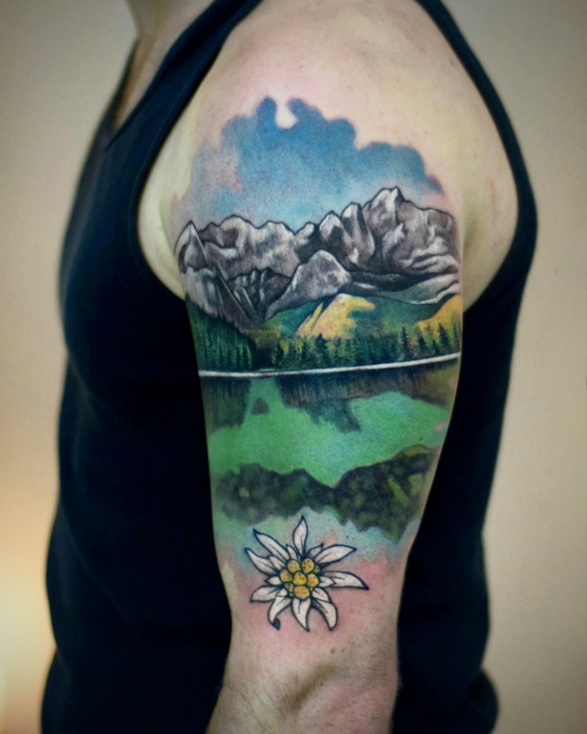 Watercolor Tattoo Deggendorf — Aquarell Bergsee mit Edelweiß Oberarm, Tattoo Studio Deggendorf Luca Limito, Atelier Voltaire Tattoo Studio / Watercolor tattoo Deggendorf — alpine lake with edelweiss on upper arm by Luca Limito at Atelier Voltaire Tattoo Studio