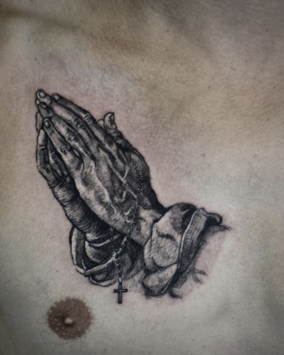 Black & Grey Tattoo Deggendorf — feine Black and Grey betende Hände mit Rosenkranz auf der Brust, Tattoo Studio Deggendorf Luca Limito, Atelier Voltaire Tattoo Studio / Black and grey tattoo Deggendorf — fine black and grey praying hands with rosary on chest by Luca Limito at Atelier Voltaire Tattoo Studio