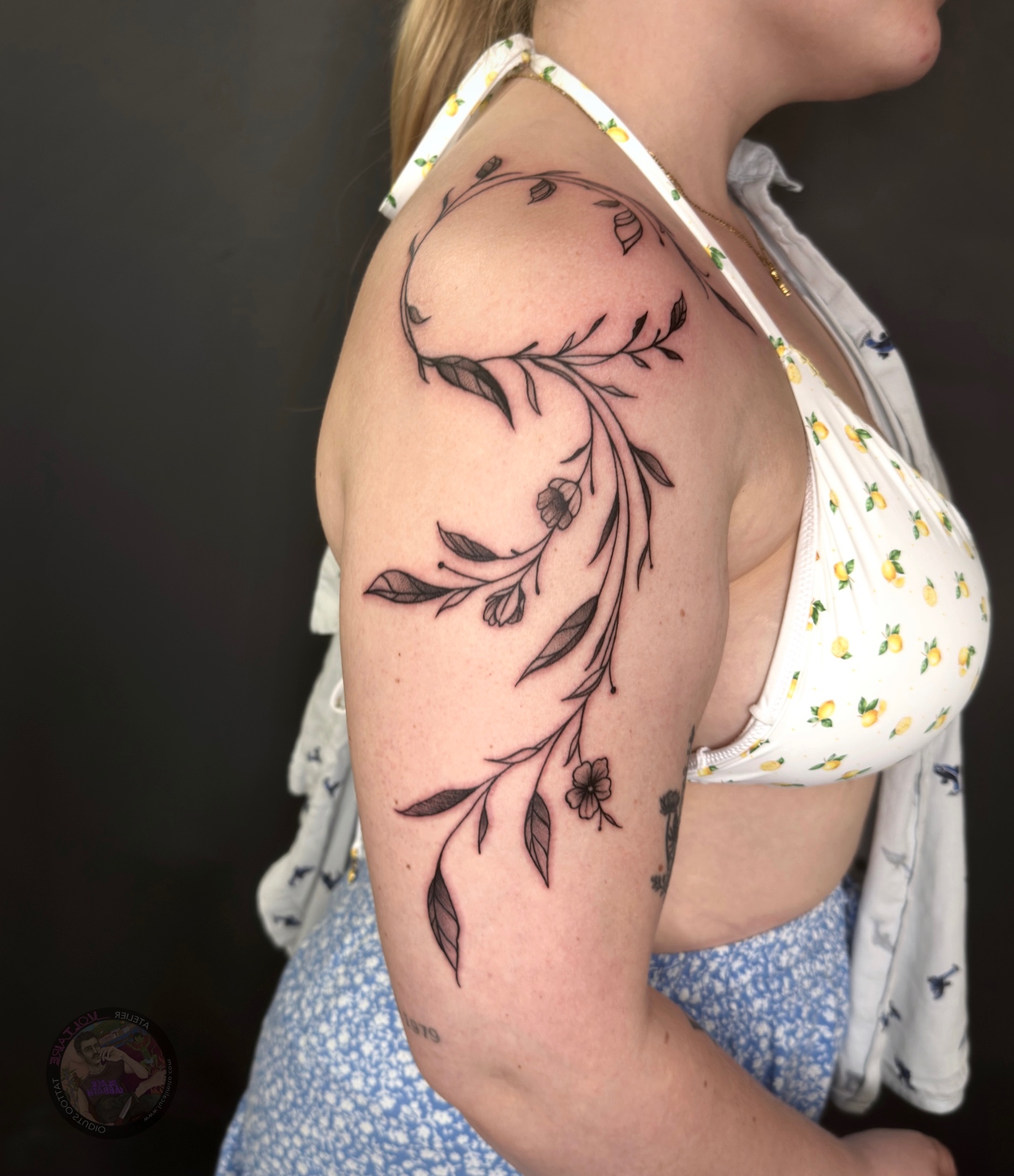 Black & Grey Botanik Tattoo Deggendorf — feines fineline Ranken-Tattoo mit Blättern und Blüten am Oberarm von Luca Limito, Atelier Voltaire Tattoo Studio / Black and grey botanical tattoo Deggendorf — fine fineline vine tattoo with leaves and blossoms on upper arm by Luca Limito at Atelier Voltaire Tattoo Studio